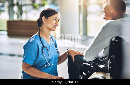 Elle sait comment égayer une journée de patients. Un médecin amical aidant un patient handicapé. Banque D'Images