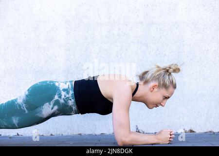Belle femme sportive se concentrant dans la salle de gym tout en faisant des exercices de remise en forme. Jeune blonde en forme parfaite faisant planche. Photo de haute qualité Banque D'Images