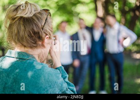 Un photographe de mariage prend des photos des invités de la mariée et du marié dans la nature, par une journée ensoleillée Banque D'Images