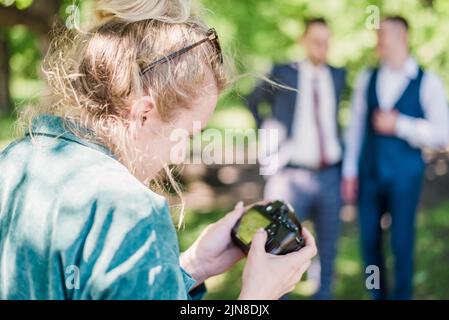 Un photographe de mariage prend des photos des invités de la mariée et du marié dans la nature, par une journée ensoleillée Banque D'Images