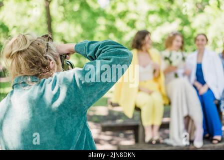 Un photographe de mariage prend des photos des invités de la mariée et du marié dans la nature, par une journée ensoleillée Banque D'Images