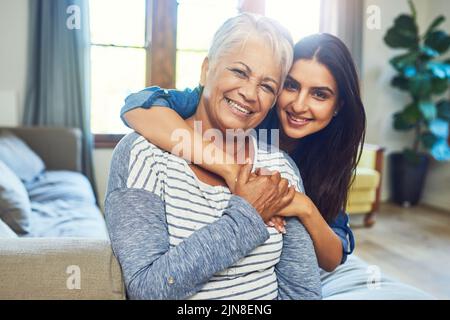 Étaient plus proches que jamais. Portrait d'une belle femme âgée posant avec sa fille tout en se relaxant sur un canapé à la maison. Banque D'Images