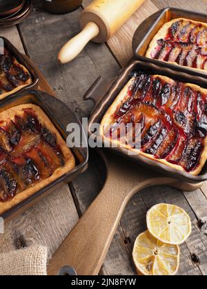 Gâteau aux prunes fraîchement cuit dans des bols en céramique sur une table de cuisine rustique, nourriture biologique, boulangerie de saison Banque D'Images