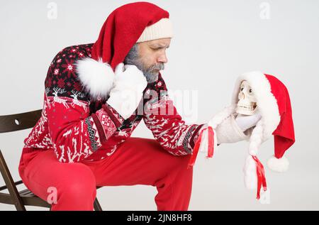 Concept vacances et Noël. Le Père Noël tient un crâne dans sa main et le regarde. Banque D'Images