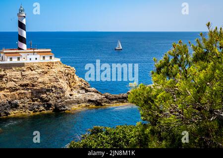 Idyllique baie de Majorque es Mular avec le phare Faro de Cala Figuera devant un voilier sur la mer méditerranée et les îles de Cabrera. Banque D'Images