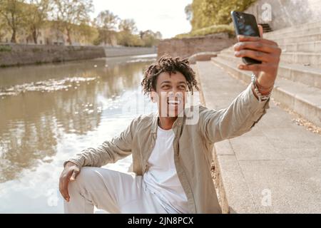 Un gars qui prend le selfie sur son smartphone près de l'eau Banque D'Images