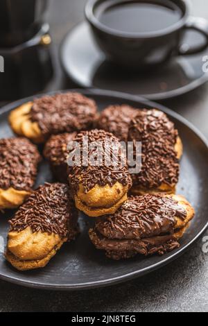 Petits fours à saupoudrer de chocolat. Mini dessert au chocolat sur une assiette. Banque D'Images