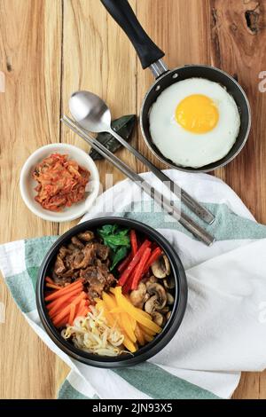 Bibimbap coréen, riz en boîte aux légumes, riz et œuf. Servi avec Kimchi. Vue de dessus sur une table en bois Banque D'Images