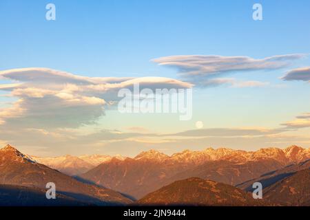 Nuage lenticulaire au-dessus des montagnes des alpes et d'une pleine lune Banque D'Images