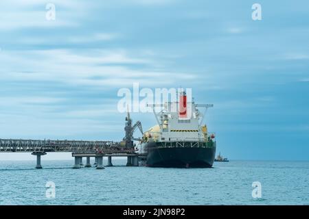 Camion-citerne de transport de gaz naturel liquéfié pendant le chargement à un terminal offshore de GNL, à la distance où le terminal d'exportation de pétrole est visible dans la mer Banque D'Images