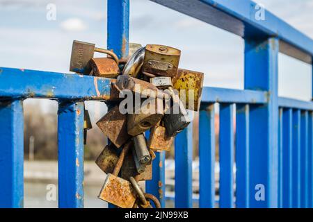 Pile de cadenas rouillés sur la clôture bleue du pont. Banque D'Images