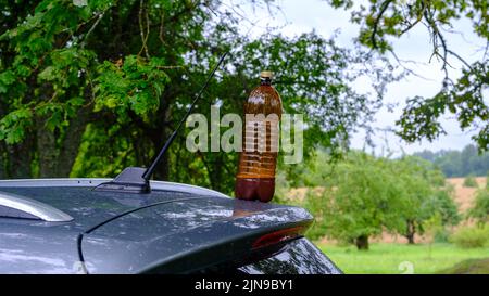 Une bouteille de bière en plastique marron sur le toit d'une voiture Banque D'Images