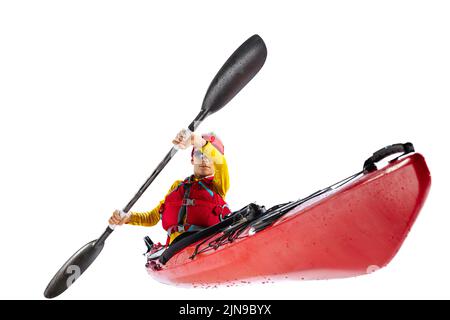 Kayakiste débutant en canoë rouge, kayak avec un gilet de sauvetage et une paddle isolée sur fond blanc. Concept de sport, nature, voyage, mode de vie actif Banque D'Images