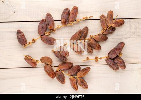 Plusieurs branches avec des dates douces sèches sur une table en bois, vue rapprochée, vue de dessus. Banque D'Images