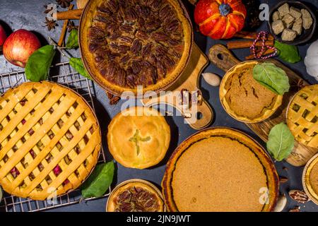 Set variété tartes d'automne.Pacanes, pommes, potiron, petits gâteaux et tartes sur fond de béton avec lumière du soleil vive, ombres sombres vue du dessus Banque D'Images