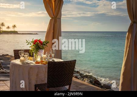 Table romantique pour deux et plage avec belvédère au coucher du soleil, Montego Bay, Jamaïque Banque D'Images