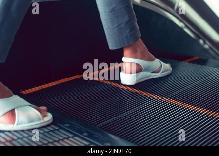 A foot stepping on an escalator at a department store. Stock Photo