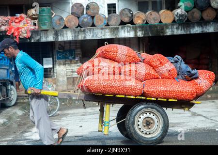 Yangon. 10th août 2022. Le 10 août 2022, un homme transporte un chariot à deux roues transportant des sacs d'oignon dans une rue du marché de gros à Yangon, au Myanmar. Credit: Myo Kyaw SOE/Xinhua/Alay Live News Banque D'Images