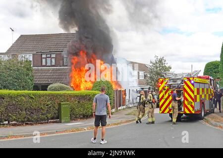 Les flammes et la fumée noire accueillent les pompiers des pompiers d'Essex, qui arrivent à la maison, les pompiers et les pompiers, avec un spectateur qui regarde le Royaume-Uni Banque D'Images