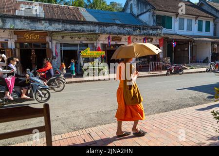 Monk avec parasol sur la rue principale à Luang Prabang, Laos Banque D'Images