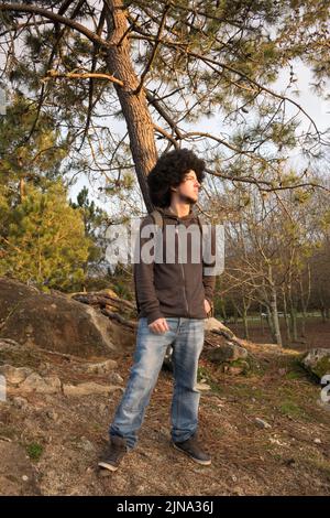 vue latérale d'un homme avec des cheveux afro regardant l'horizon dans la forêt Banque D'Images
