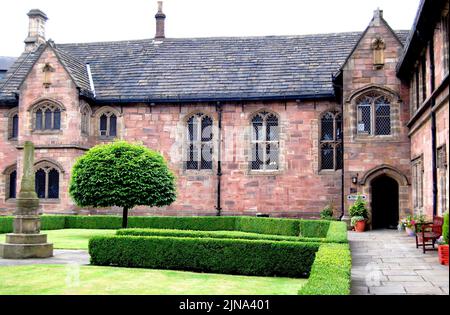 La salle Baronial de l'école de musique de Chethams, Manchester, Royaume-Uni, construite au XVe siècle, avec Hyde Cross au premier plan sur la gauche. Le bâtiment inclut actuellement la bibliothèque. La croix est apparue sur une carte de Manchester en 1650 en tant que croix latine sur un piédestal et se trouvait à un carrefour routier voisin jusqu'aux années 1840. Chetham's enseigne aux élèves et aux étudiants âgés de 8 à 18 ans. La bibliothèque de Chetham est la plus ancienne bibliothèque de référence publique gratuite du monde anglophone. Banque D'Images