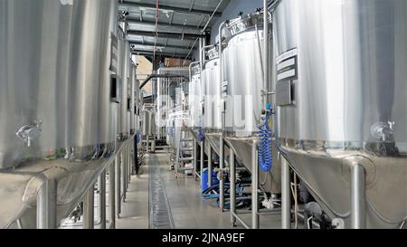 Rangée de cuves de micro-brasserie en métal brillant ou cuves de fermentation en purée dans l'usine de brasserie. Usine de bière moderne avec bouilloires, tubes et réservoirs à brasseur Banque D'Images