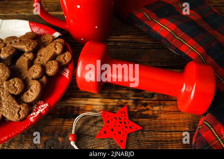 Dumbell, biscuits d'homme de pain d'épice sur l'assiette en forme de Père Noël, Noël bas, ornement, mug. Gym fitness vacances concept de saison, composition de régime d'ajustement. Banque D'Images