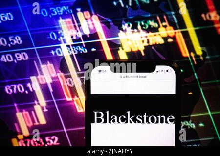 KONSKIE, POLOGNE - 09 août 2022: Smartphone affichant le logo de la société du Groupe Blackstone sur fond de diagramme boursier Banque D'Images