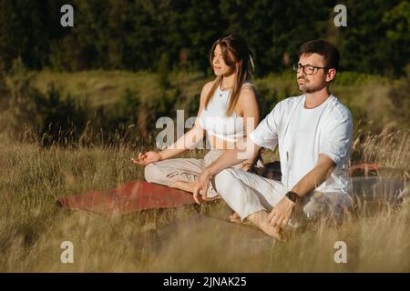 Femme caucasienne et homme vêtus respiration de l'air frais dans la nature, jeune couple adulte méditant à l'extérieur Banque D'Images