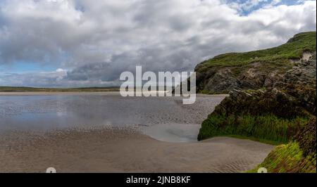 Vue sur la pittoresque plage de sable doré de Maghera avec des rochers et des falaises recouverts d'algues au premier plan Banque D'Images