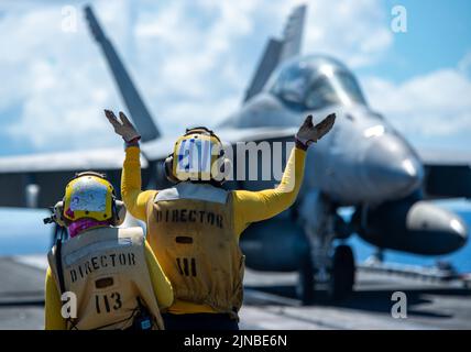 Océan Pacifique, États-Unis. 07th août 2022. Les directeurs de vol de la Marine américaine signalent au pilote d'un avion de chasse F/A-18E Super Hornet attaché au Dambusters of Strike Fighter Squadron 195 de se positionner pour le décollage sur le pont de vol du porte-avions de la classe Nimitz USS Ronald Reagan en cours, 7 août 2022 en mer des Philippines. Crédit: MC3 Gray Gibson/Planetpix/Alamy Live News crédit: Planetpix/Alamy Live News Banque D'Images