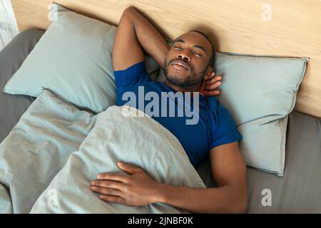 Photo en grand angle d'un homme noir dormant dans la chambre Banque D'Images