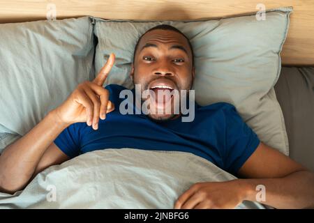 Un homme afro-américain excité ayant l'idée couché dans la chambre à coucher Banque D'Images