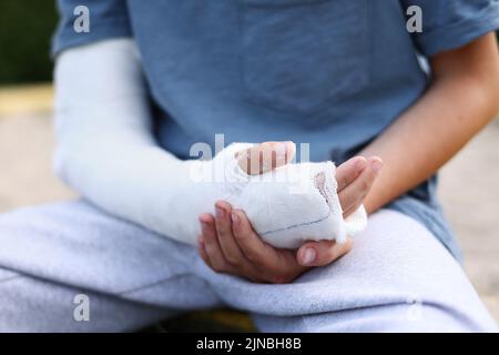 le bras d'un enfant est cassé. petit garçon avec un membre fracturé à l'extérieur. blessure par fracture pendant les vacances d'été. enfant se déplace les doigts dans le plâtre coulé sur le th Banque D'Images