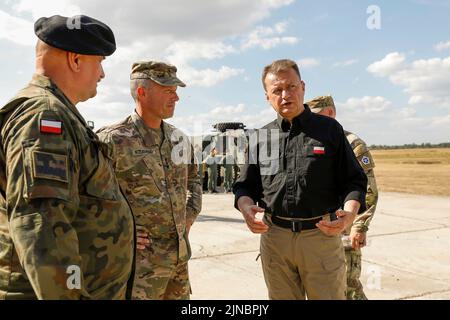 Biedrusko, Pologne. 10th août 2022. Le ministre polonais de la Défense, Mariusz Blaszczak, à droite, s'entretient avec le général de corps d'armée des États-Unis, John Kolasheski, commandant général du corps V, et le général des Forces terrestres polonaises Jaroslaw Mika, qui sont partis lors de la cérémonie d'ouverture de l'Académie d'entraînement de chars d'Abrams au Centre d'entraînement des forces terrestres de 10 août 2022 à Biedrusko, en Pologne. L'académie d'entraînement de char d'Abrams a été créée pour enseigner aux membres de équipage polonais sur les opérations, les tactiques et l'entretien du char de bataille principal d'Abrams de M1. Crédit: SPC. Hassani Ribera/Armée des États-Unis/Alamy Live News Banque D'Images