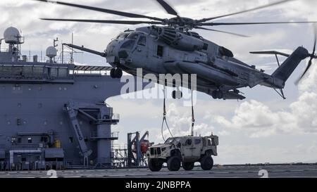 Marines des États-Unis avec le Medium Tiltrotor Squadron 262 (rein.), 31st Marine Expeditionary Unit place un véhicule tactique léger conjoint sur la base mobile expéditionnaire USS Miguel Keith (ESB-5) en utilisant un Super Stallion CH-53E lors d'un exercice d'équipe de soutien d'hélicoptère en mer des Philippines, le 8 août 2022. Les HSTs permettent de configurer une zone de dépôt rapide pour le ramassage et le transport d'équipements lourds en vol. Le MEU de 31st opère à bord de navires du Groupe amphibie Ready de Tripoli dans la zone d'opérations de la flotte de 7th pour améliorer l'interopérabilité avec les alliés et les partenaires et servir de réponse prête à l'emploi Banque D'Images