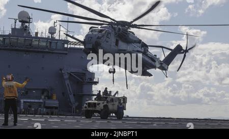 Les Marines des États-Unis, qui ont 262 escadrons de Tiltrotor moyens (rein.), et le bataillon de logistique de combat 31, 31st Marine Expeditionary Unit, fixent un véhicule tactique léger conjoint à un CH-53E Super Stallion à bord de la base mobile expéditionnaire USS Miguel Keith (ESB-5) lors d'un exercice d'équipe de soutien d'hélicoptère en mer des Philippines, le 8 août 2022. La transmission hydrostatique permet la configuration d'une zone de dépôt expéditive pour le ramassage et le transport d'équipement lourd en vol. Le MEU de 31st opère à bord de navires du Groupe amphibie Ready de Tripoli dans la zone d'opérations de la flotte de 7th afin d'améliorer l'interopérabilité avec les alliés et les partenaires Banque D'Images