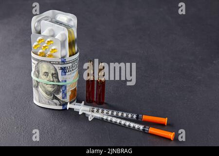 Les pilules, les ampoules et les seringues sont enveloppées dans des billets de dollars, fixés avec une bande élastique sur un fond noir. Hausse des prix des médicaments et des produits pharmaceutiques m Banque D'Images