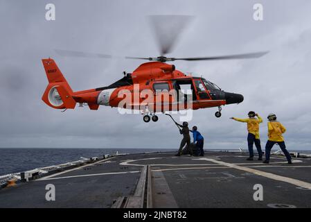 Garde côtière américaine Petty Officer 1st classe Josh Trommer, à gauche, un technicien d'entretien de l'aviation affecté à la station aérienne de la Garde côtière Houston, relie l'élingue de levage au crochet de chargement de l'hélicoptère pendant les opérations de réapprovisionnement vertical (VERTREP) avec l'équipage d'hélicoptère MH-65 Dolphin à bord du célèbre couteau d'endurance moyenne USCGC Mohawk (WMEC 913) en cours dans l'océan Atlantique, le 7 août 2022. USCGC Mohawk est en déploiement prévu dans la zone des opérations de la Marine américaine en Afrique, employée par la Sixième flotte américaine pour défendre les intérêts américains, alliés et partenaires. (É.-U. Garde-côtes Banque D'Images