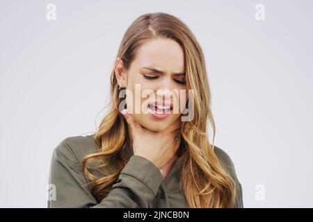 Si vous avez l'impression que quelque chose est coincé là-bas. Photo en studio d'une jeune femme souffrant d'un mal de gorge sur fond gris. Banque D'Images