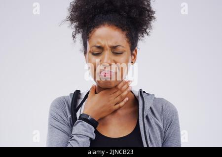 Dégager ma gorge avant du dire. Photo en studio d'une jeune femme souffrant d'un mal de gorge sur fond gris. Banque D'Images