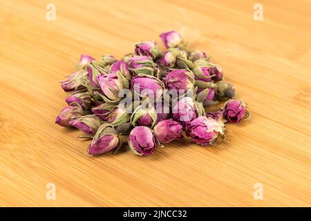 Boutons roses déshydratés sur une planche à découper en bois Banque D'Images