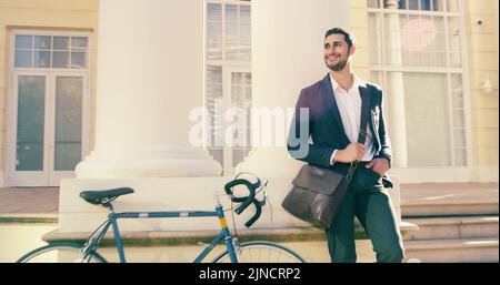 Ce temps a mis tout le monde de bonne humeur. Un beau jeune homme d'affaires qui se pose à côté d'un vélo dans la ville. Banque D'Images