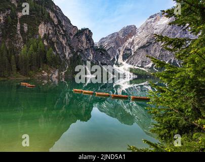 Le mont Seekofel et les bateaux à la lumière du soir, se reflétant dans l'eau claire et calme du lac de montagne emblématique Pragser Wildsee (Lago di Braies) dans les Dolomites Banque D'Images