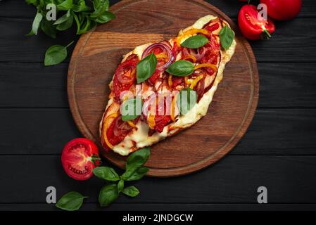 Pain plat de pizza sans gluten. Pizza sur un pain plat avec des légumes sur fond de bois noir. Vue de dessus Banque D'Images