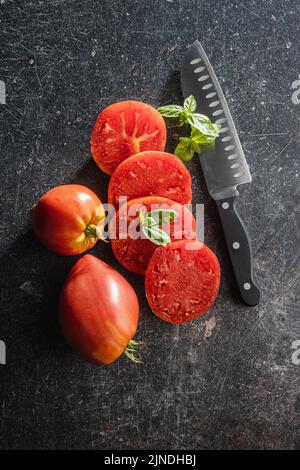 Tranches de tomates coeur de taureau sur une table noire. Vue de dessus. Banque D'Images