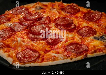 Gros plan, macro : pizza au pepperoni maison brûlée sur plateau dans un four électrique Banque D'Images