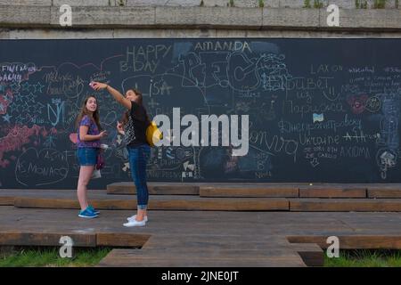 Deux filles prennent un selfie avec ce qu'elles ont écrit sur le tableau de surveillance interactif près de la Seine. Belle journée d'été en plein air à Paris, France. Banque D'Images