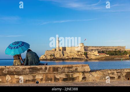 LA HAVANE, CUBA - JANVIER 2 : deux femmes assises sous un parapluie bleu au port de 2 janvier 2021 à la Havane, Cuba Banque D'Images